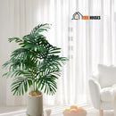 Palm Tree  Realistic Tropical  Artificial - The plant is in a well-lit room next to a white upholstery. Height: 80cm, 18 leaves. Vibe Houses