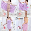 Bath towel with wearable handle for women; Colour; Purple; how to use; the model shows it in four images; 1 Open fully at the back holding with open arms; 2 Place a strap on one of the shoulders; 3 Put the other strap on the other shoulder; 4 ready; note that on the back it is open; vibe houses