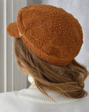 Cap | Sailor's cap, worn on a woman's head. The woman is facing away from the camera. It allows you to see the back of the beret. Brown color. vibe houses