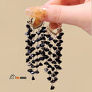Earrings with black crystal tassel pendant ✨ The woman holds the pair of earrings in one hand; vibe houses