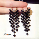 Earrings with black crystal pendant ✨ The woman holds the pair of earrings in one hand vibe houses