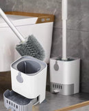 Toilet brush with long handle and drain base. Image inside a bathroom showing two toilet brushes and two drain bases, one near the toilet; vibe houses