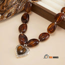Necklace | Heart-shaped choker: Modern romance with a bold touch, brown color, on the table; vibe houses