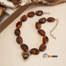 Necklace | Heart-shaped choker: Modern romance with a bold touch, brown color, on the table; vibe houses