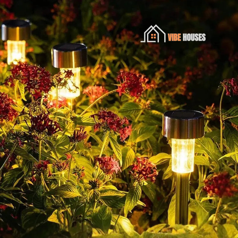 Solar-powered garden lights; Image of three four Black Shell-Warm among flowers. Vibe Houses