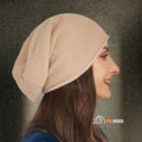 CozyMuse women's beanie. Woman with her face turned to the side, smiling, wearing a beige beanie. vibe houses