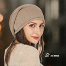 CozyMuse women's beanie. Woman with her face turned to the side, looking directly at the camera, wearing a beige beanie. vibe houses