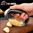 Premium stainless steel garlic press! Mashing garlic being used on a wooden cutting board; Vibe Houses