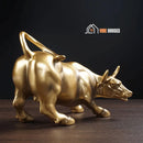 Wall Street Bull Statue - Golden; this shows the back part; On a wooden table all the beauty of the statue stands out; vibe houses