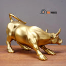 Wall Street Bull Statue - Golden; This one is sideways; On a wooden table, the beauty of the statue stands out; houses with a vibe;
